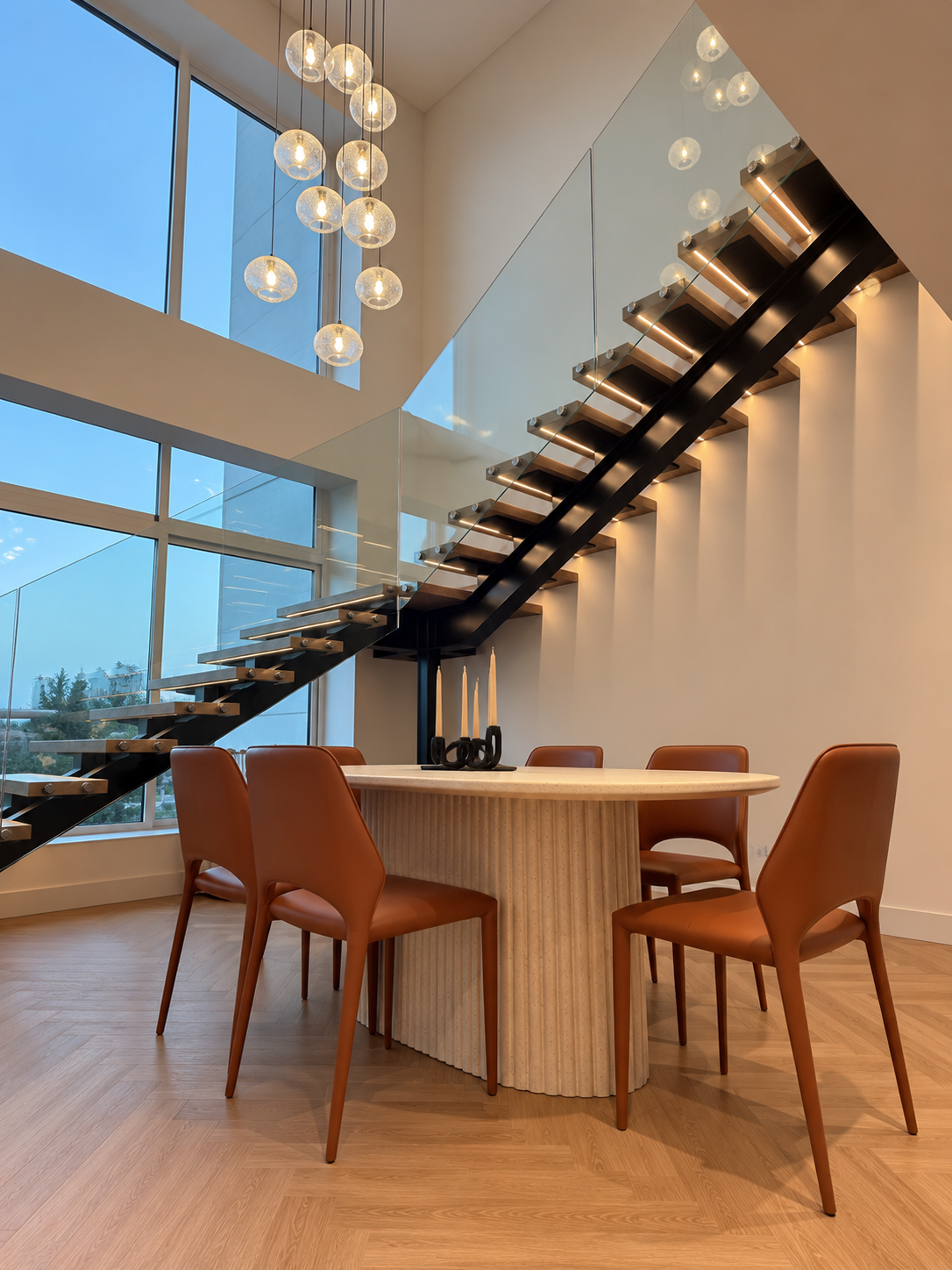 Dining area with floating staircase, orange leather dining chairs, and statement chandelier