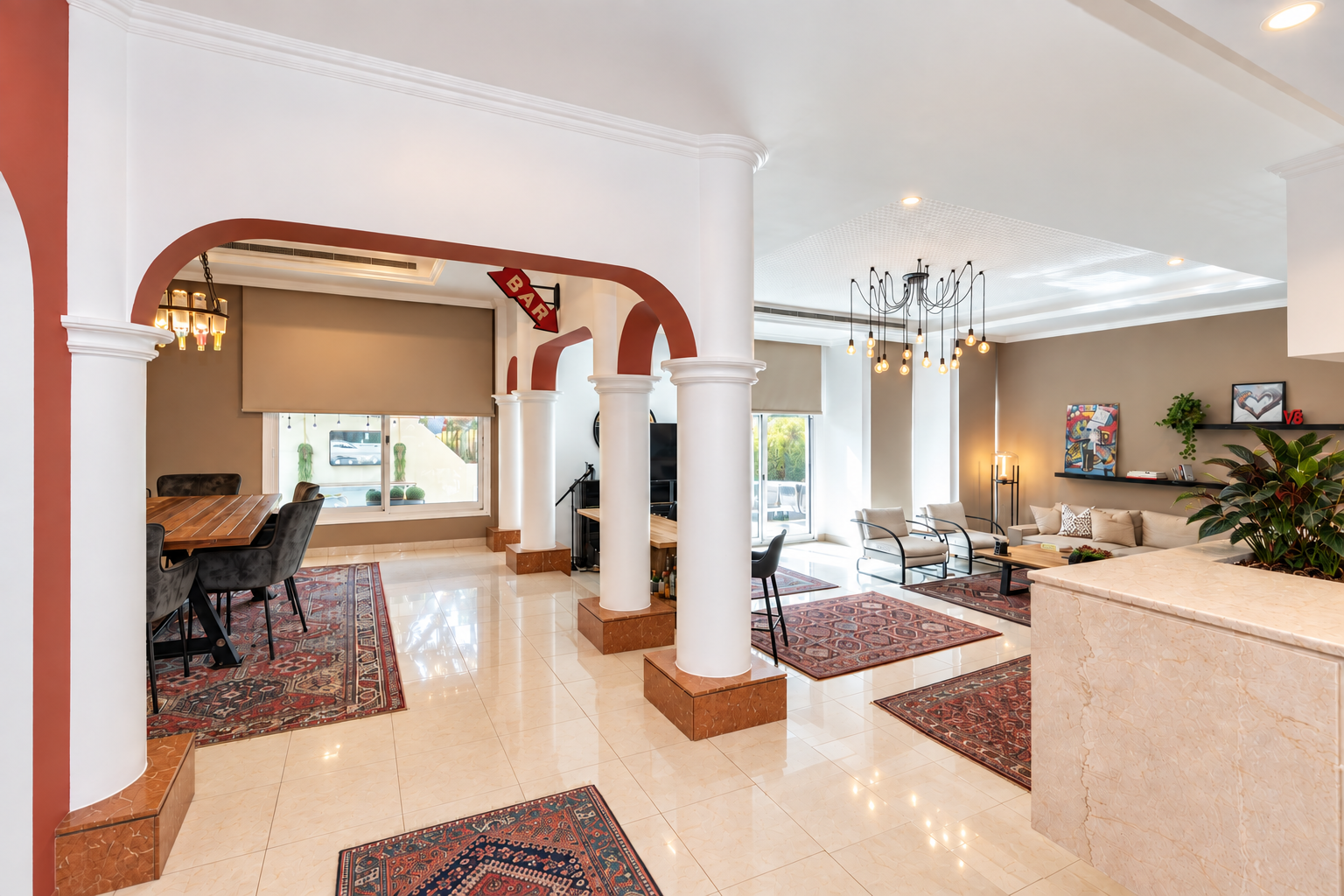 Open-concept living area with terracotta-accented arched colonnades dividing the dining space from a contemporary living room layered with traditional Persian rugs